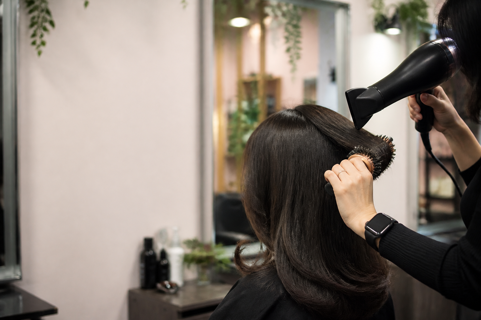 Illustrative editorial photograph of a blow-dry being finished with a round brush.