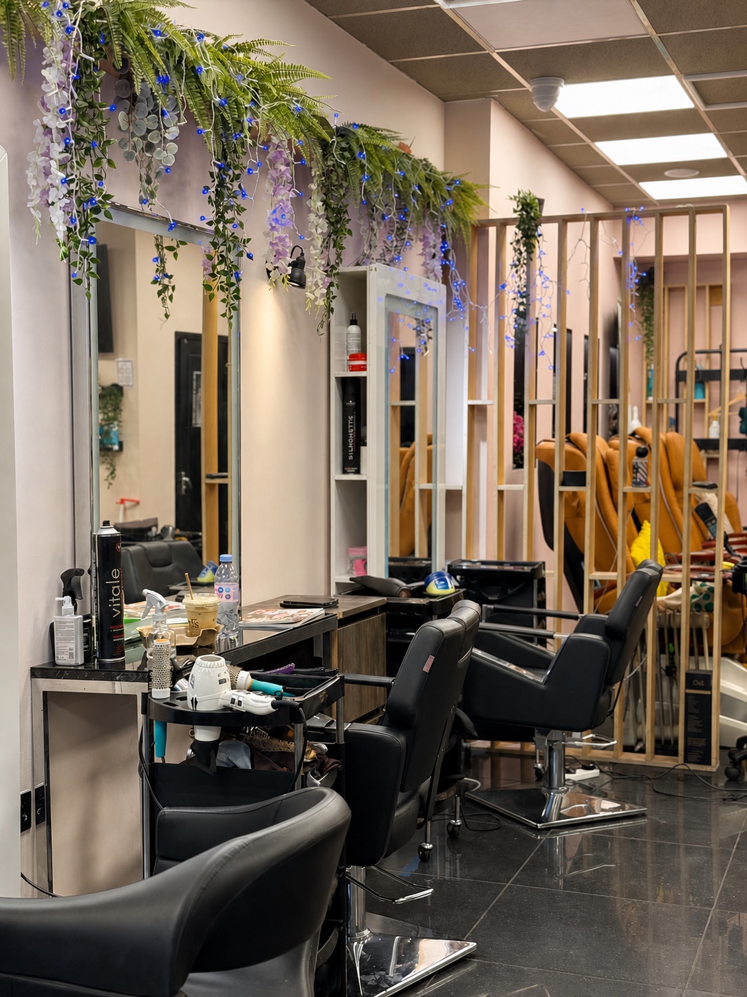 Row of professional styling stations with floral greenery.